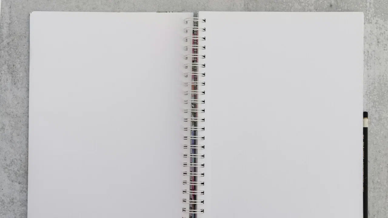 An opened notebook with handwriting, lying on a pale surface