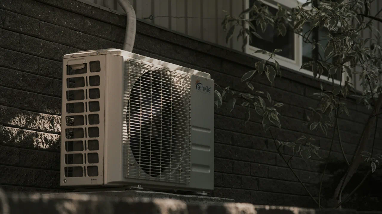 A white air conditioning unit mounted on a brick wall