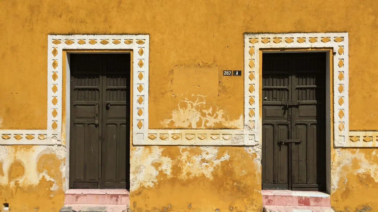 Two tall wooden doors set into a weathered ochre colonial facade