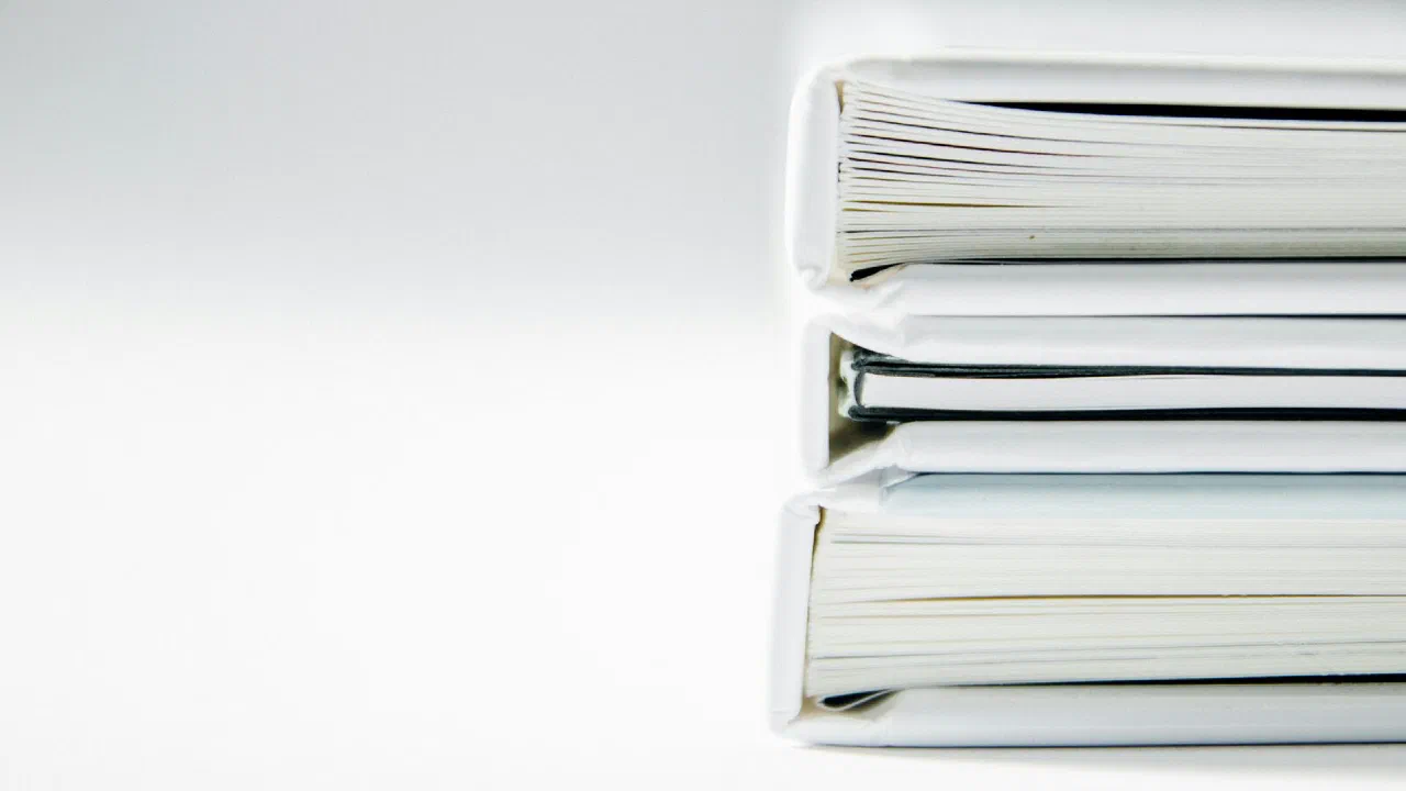A stack of thick paper folders on a white surface